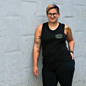 woman wearing black it's ok to give a fuck tank top standing against wall