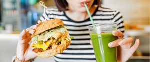 woman eating a veggie burger and drinking green smoothie