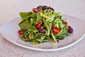 green pasta with spinach tomatoes and olives