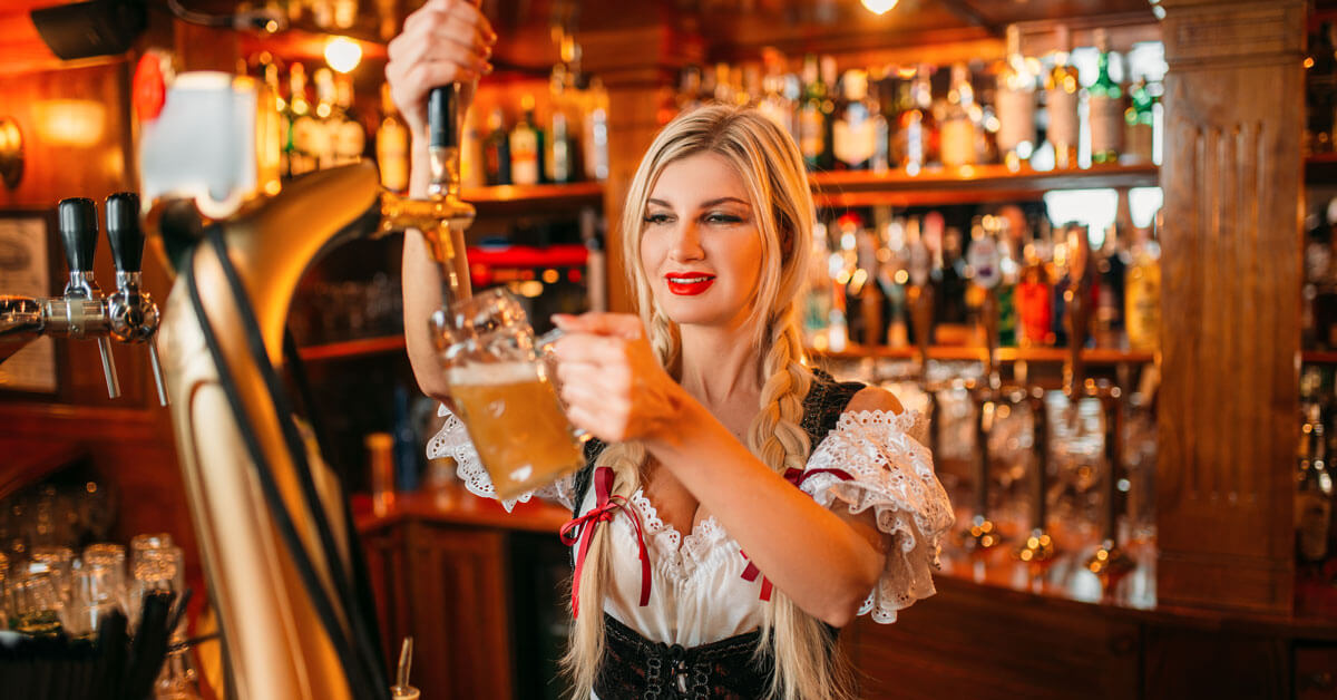 Blond barmaid wearing Dirndl type dress pouring beer