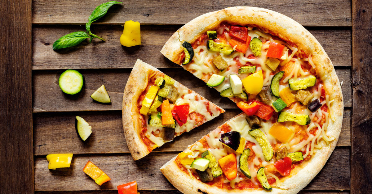 Vegan pizza with Miyoko's vegan cheese on wooden background with Zucchini peppers basil and aubergine