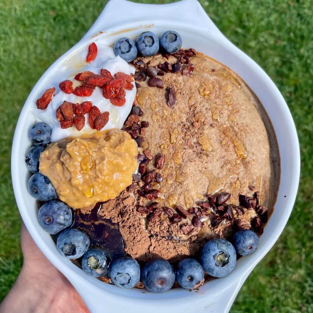 nutriciously baked oatz topped with blueberries peanut butter cacao vegan yogurt sauce dried red berries
