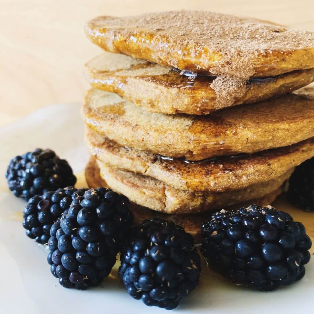 stack of pumpkin oat pancakes with syrup and blackberries