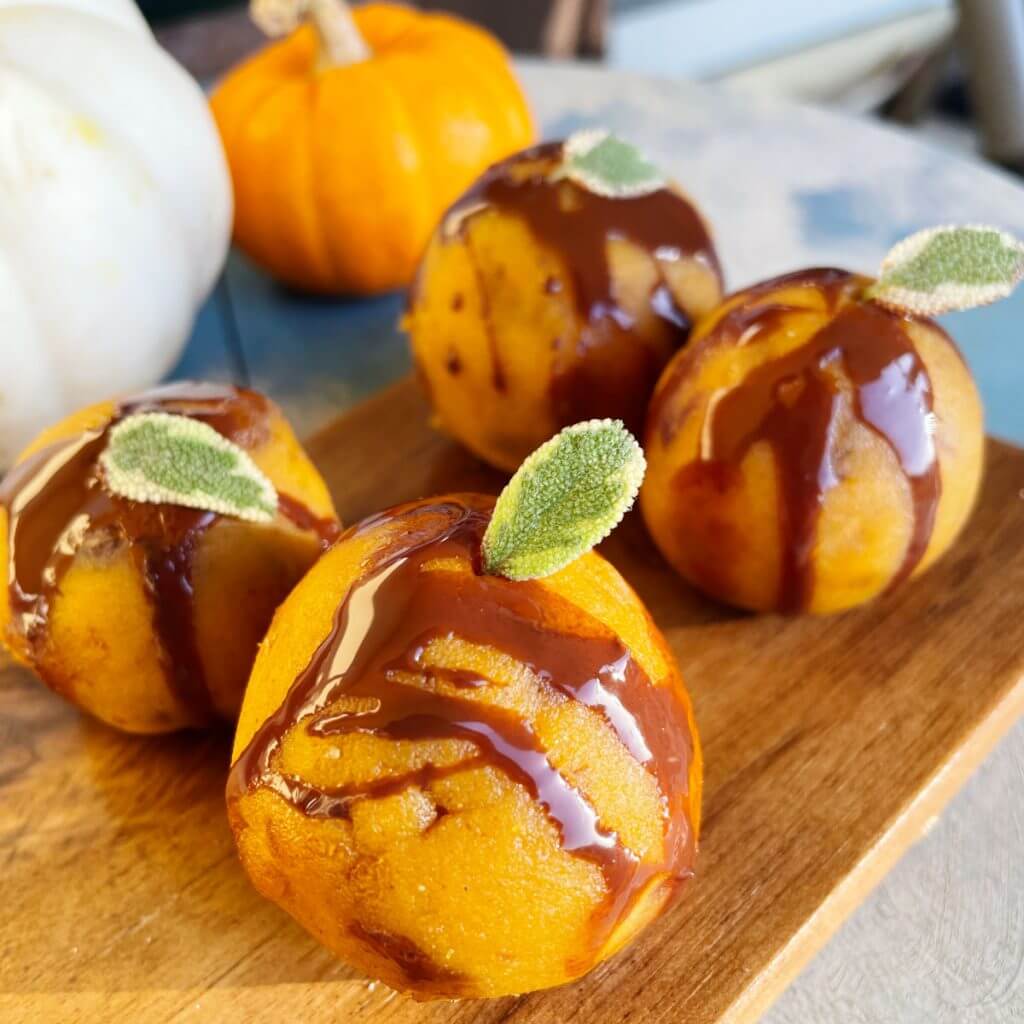 four pumpkin pier energy bites dripping in caramel glaze topped with leaf