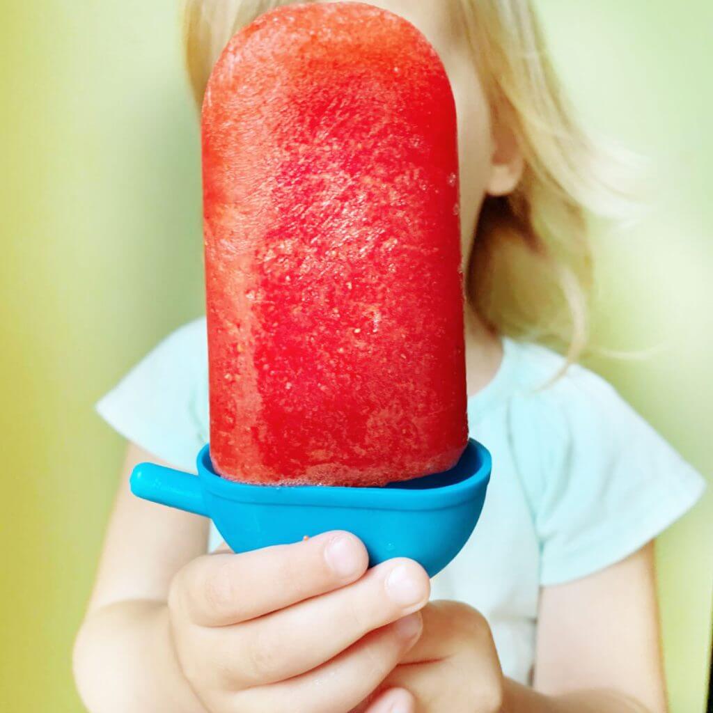 young girl holding frozen fruit pop