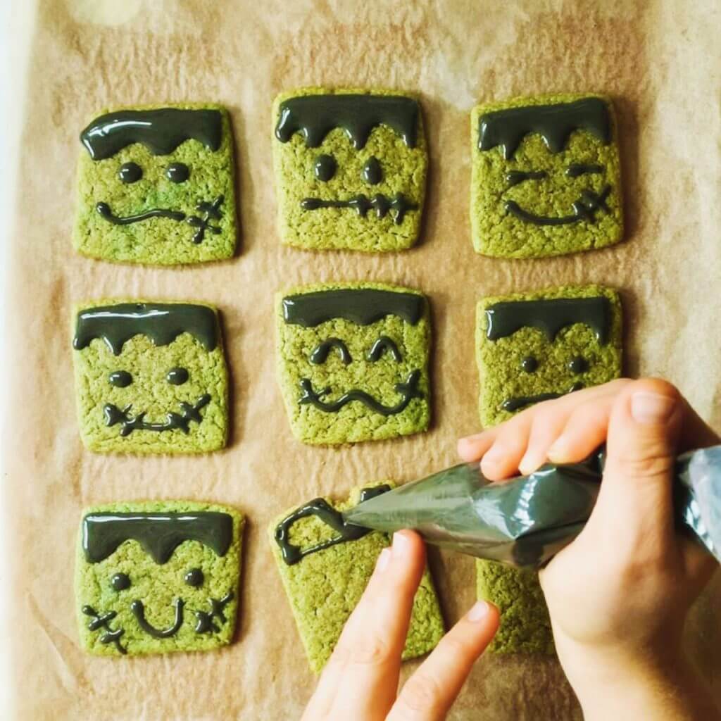 diy frankenstein vegan matcha sugar cookies hands piping green frosting