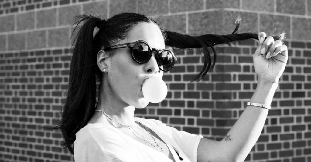 girl with sunglasses blowing bubble with gum