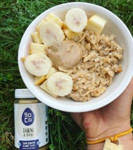 soco tahini and dates dollop on bowl of oats with banana slices apple chunks