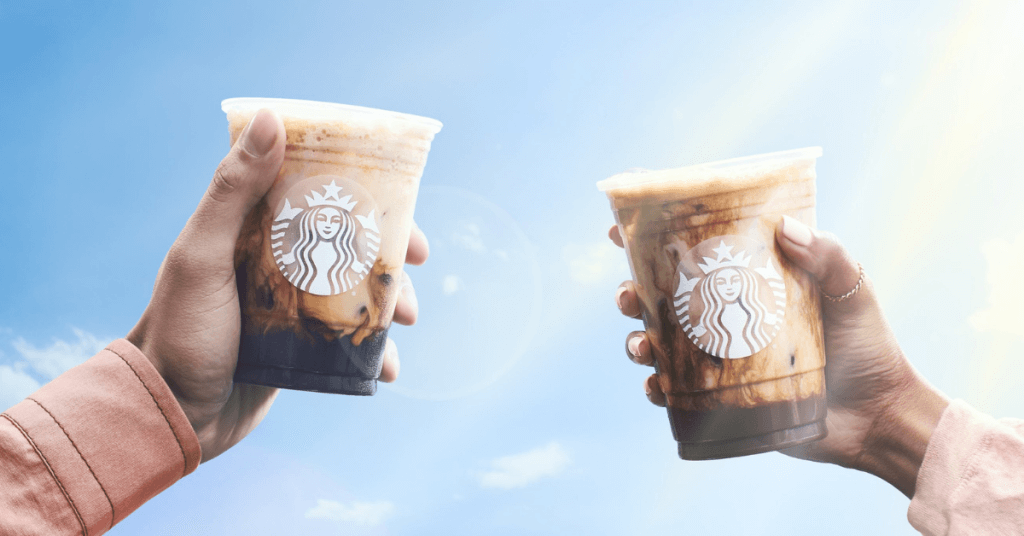 Two hands holding up Starbucks cups