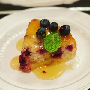 cake dessert topped with blueberries and a mint leaf