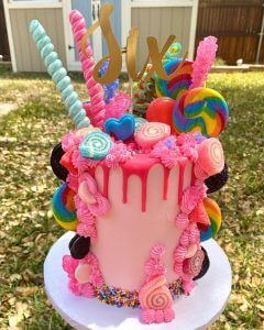 Pink cake topped with assorted candy and a Six topper