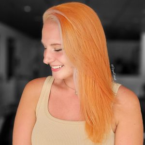 vegan colorist smiling woman with soft orange hair face framing white highlights