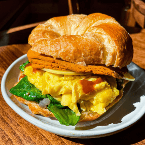 vedge co breakfast croissant sandwich with vegan egg and deli slices