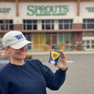Doozy Pots worker in a Doozy Pots hat holds Doozy Pots ice cream package outside of Sprouts